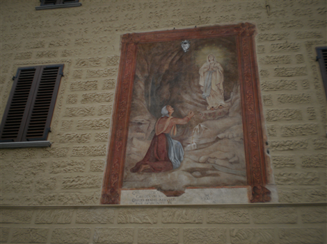 Affresco raffigurante l'Apparizione della Madonna di Lourdes a Bernardette sulla facciata della "Casa del Canonico" in Piazza Castello
